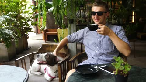 Handsome Man Drinking Coffee In Cafe With His Dog