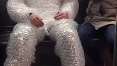 Man wrapped in bubble wrap red helmet on train
