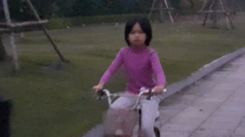 Baby girls drive bicycle first then dog runs after