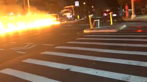 Car Pushes Flaming Motorcycle down Street