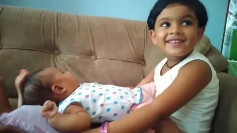 The cute little sister tries to put the baby to sleep by singing a song