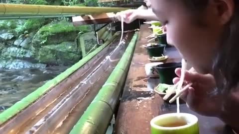 Would you eat noodles falling from a bamboo slide while sitting in front of a waterfall?🤔