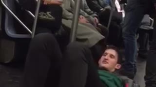 Man laying on floor pretending to walk on subway pole