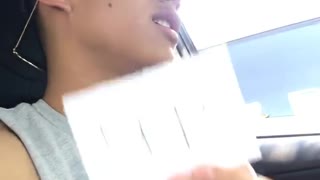 Guy in car holds a paper up sign