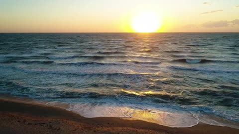 Waves in the sea from a beach during a sunset