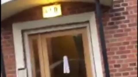 Blue shirt black jeans on top of door way outside falls tyring to get down