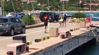 Man in orange and black carries small weights on dock