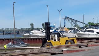 Large Forklift Lowering a Boat Into the Water at a Dry Dock Marina