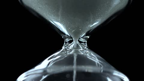 Glass hourglass close up on a black background