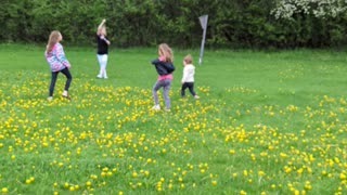 Girls watching a friend fly a kite.