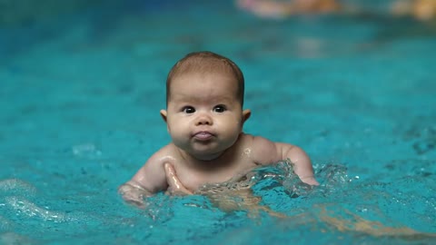 Little baby learning to swim in a pool