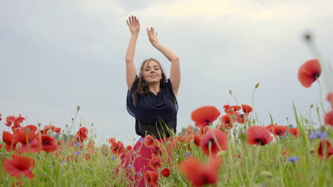 Dancing happily in the middle of a field of pink and blue flowers, during a bright day.