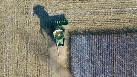 4K Drone Following Agricultural Machine in the Field From Above While it is Harvesting.