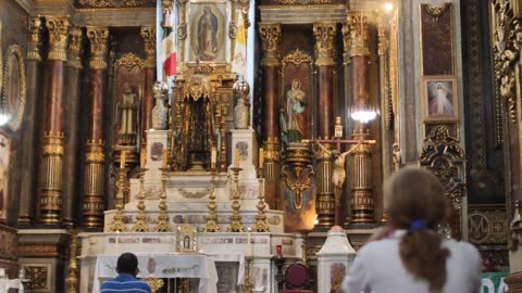 Lady praying in front of a large altar inside a church