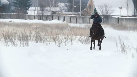 Young woman galloping on snowly outdoor on red horse