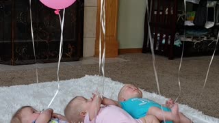 Triplets Playing with Balloons