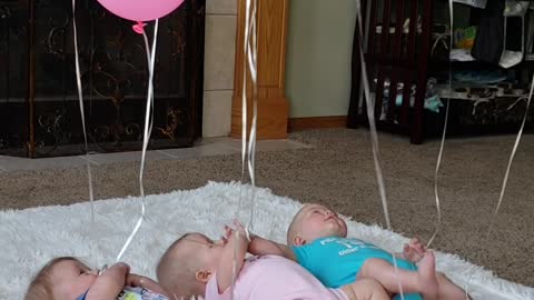 Triplets Playing with Balloons
