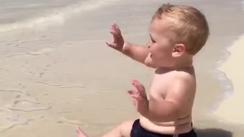 Cute baby on the beach playing and shouting