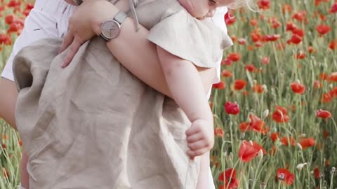 Woman Carrying Her Baby While Standing on Red Poppy Flower Field