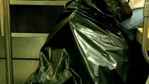 Person white headphones looking through big black trash bag