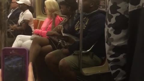 A man in a blue sweater singing on subway train