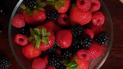 Red berries served in a bowl on a wooden table - vertical video