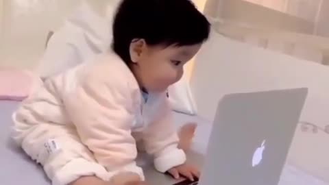 Adorable baby using laptop and doing work .