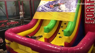 Guy on blow up slide falls off the cover and falls down slide