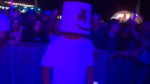 Music guy films a man in a white mask dancing at a rave