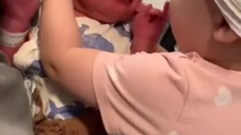 One-year-old girl excitedly meets her newborn baby brother