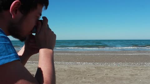 Man photographing the sea in a sunny beach