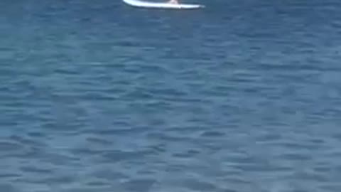 Guy on knees stands up on white paddleboard
