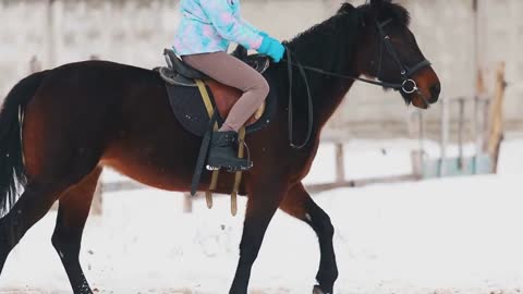 A young woman riding a brown horse in a village