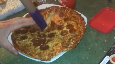 Guy cutting pizza with swiffer handle bar