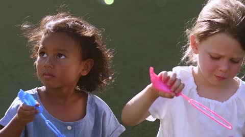 Two Cute Girls Blowing Bubbles