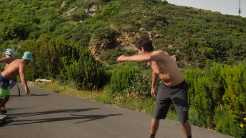 A group of skating guys skating on a road near the mountains