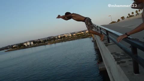 Shirtless guy front flip off bridge slaps back