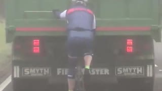 Cyclist Hitching a Ride Holding onto a Truck