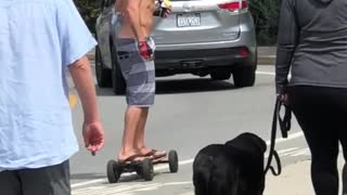 Shirtless guy rides a motorized skateboard on side street