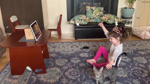 Little girl adorably struggles with remote learning due to affectionate cute kitten