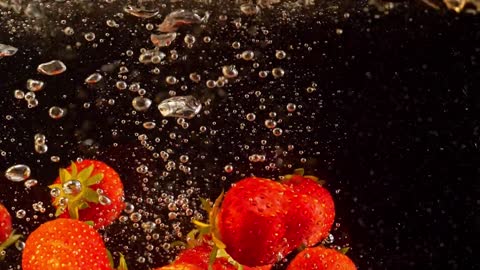 Slow motion - strawberries falling into water