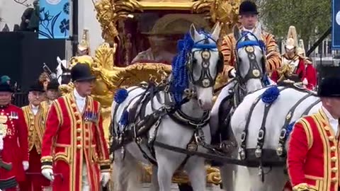 King Charles and Queen Consort Camilla greet onlookers during coronation procession