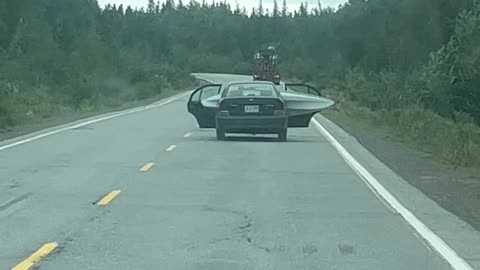 Car Driving on Road with Kayak in Back Seat