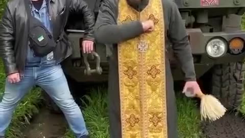 A "priest" of the Zelensky's schismatic church lifting fist while blessing armoured vehicle