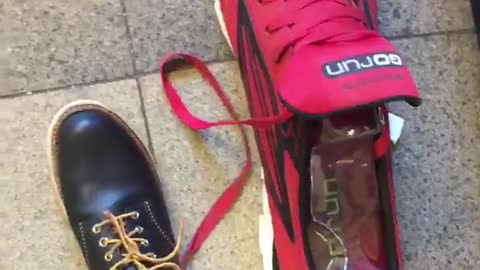 Man with black shoe compares foot to red tennis shoe