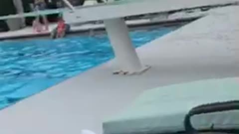 Little boy red swim shorts flips off diving board