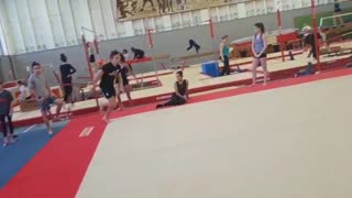 Gymnast does a flip on platform and falls, laughs