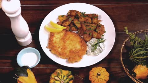 Vienner Schnitzel with side dish baked potatoes and cucumbers dill creamy yogurt salad