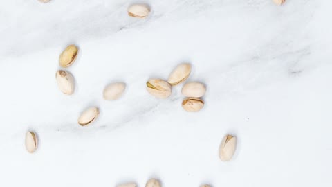 Spreading Widely A Handful Of Pistachio Nuts Over A Marble Surface