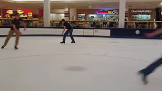 A guy falls lands on arms and legs trying to ice skate